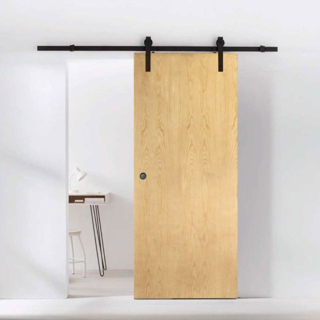 puerta corredera lisa fabricada en madera de pino instalada en una habitacion moderna