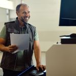 feliz carpintero trabajando con una computadora en el taller